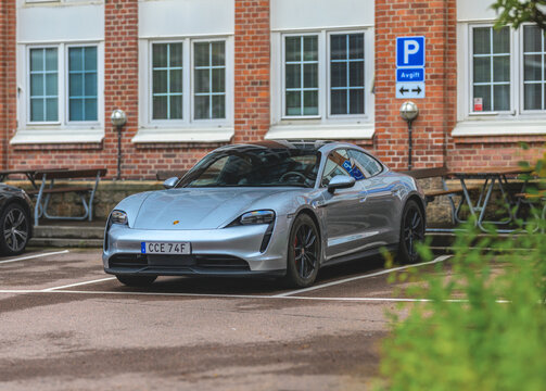 Gothenburg, Sweden - August 29 2026: Silver Porsche Taycan electric sports car parked by brick building.