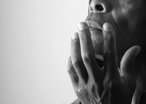 praying to god with hands showing his religious faith with God Caribbean man praying with background with people stock photo stock image