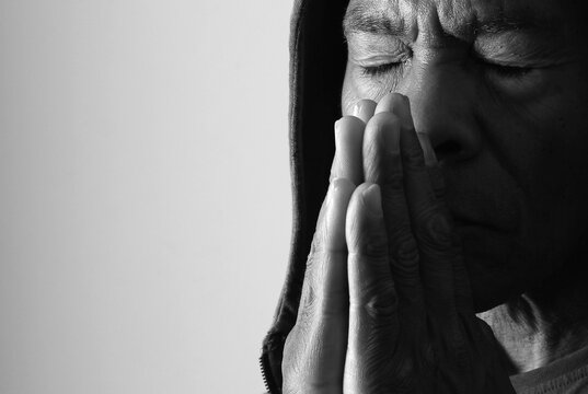 praying to god with hands showing his religious faith with God Caribbean man praying with background with people stock photo stock image