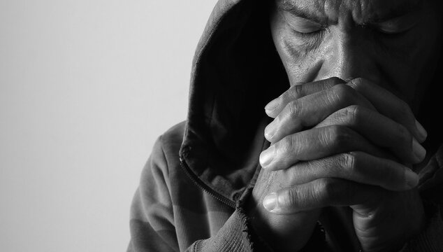 praying to god with hands showing his religious faith with God Caribbean man praying with background with people stock photo stock image