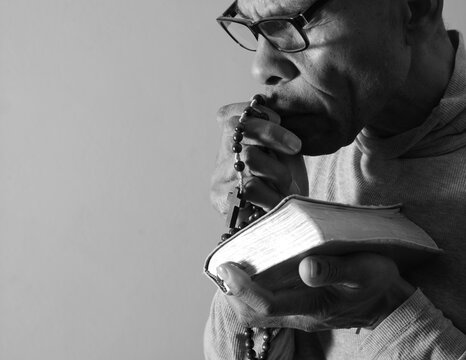 praying to god with hands showing his religious faith with God Caribbean man praying with background with people stock photo stock image