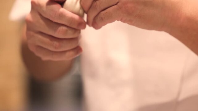Two hands passing a freshly shaped dumpling piece