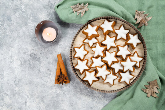 Christmas holiday sweets, homemade cinnamon stars with hazelnuts and almonds, cookies and biscuits with icing glaze, candle light 