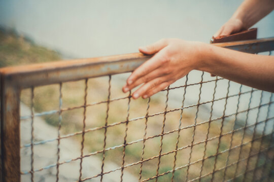 Close-up of hands using a sanding block to smooth a rusty metal fence before painting. Motion blur adds a raw, authentic feel. DIY restoration photo for craft and renovation projects