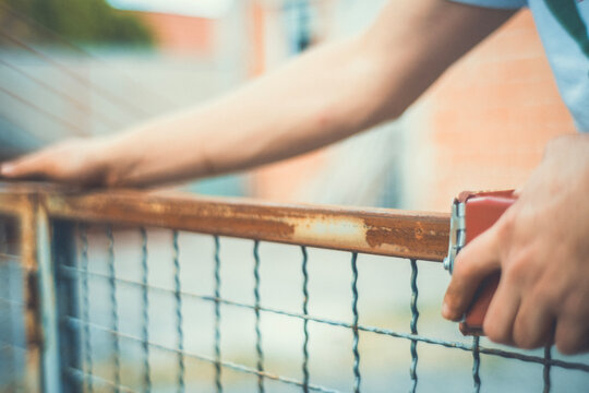 Close-up of hands using a sanding block to smooth a rusty metal fence before painting. Motion blur adds a raw, authentic feel. DIY restoration photo for craft and renovation projects