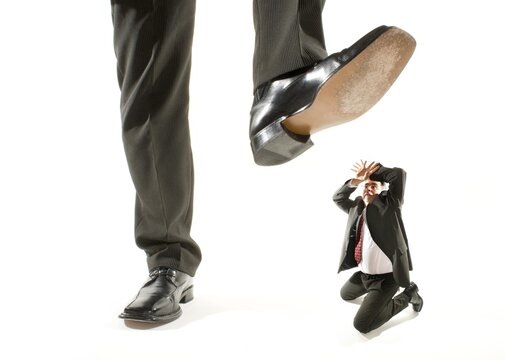 Giant foot stepping on a kneeling businessman
