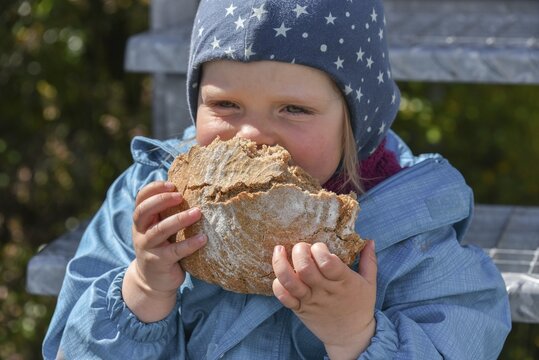 Little girl biting heartily into a black bread, Chile