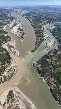 Aerial View of a Large River Confluence where Two Different Colored Water Streams Meet Near Farmland and Fields
