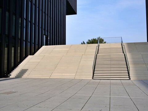 Modern urban architectural stairs and outdoor steps with sleek black office building facade under clear blue sky in contemporary business district