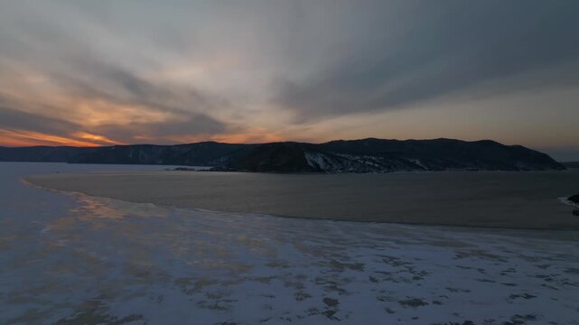High angle view of the confluence where the open water of Angara River meets the frozen ice sheet of Lake Baikal near Listvyanka in Irkutsk Oblast, Russia at winter twilight