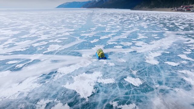 High angle aerial view showing an amphibious hovercraft cruising across the vast frozen ice surface of scenic Lake Baikal in Irkutsk Oblast Russia during cold winter season