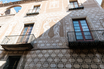 A historic building facade features intricate white sgraffito murals and iron balconies under sunlight. © @dsokol66