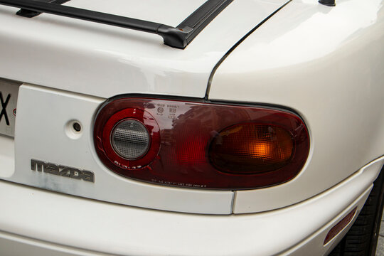 GANDIA, SPAIN - OCTOBER 4, 2026 Detail of the rear taillight and logo of a classic white Mazda MX-5 Miata first generation NA roadster sports car.
