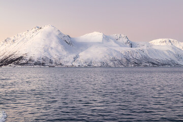 Snow-capped mountain range rising from fjord during polar twilight in Northern Norway © Alberto