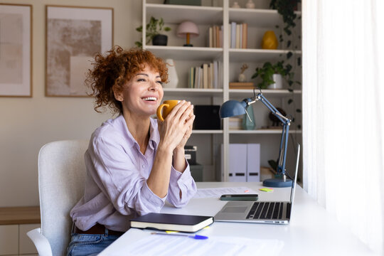 Smiling woman enjoying coffee break while working from home