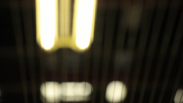 Thin metal wires backlit fluorescent lamps. Old factory ceiling dark low angle.