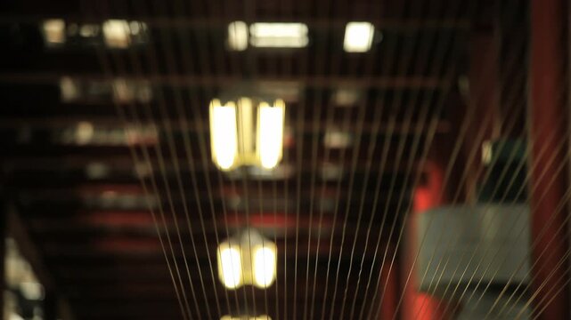 Converging wires factory hall closeup. Rack focus parallel strands dark plant.