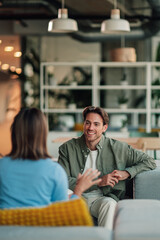 Obraz na płótnie Canvas Young man smiling and communicating with a woman in an informal office meeting, discussing business in a modern workplace