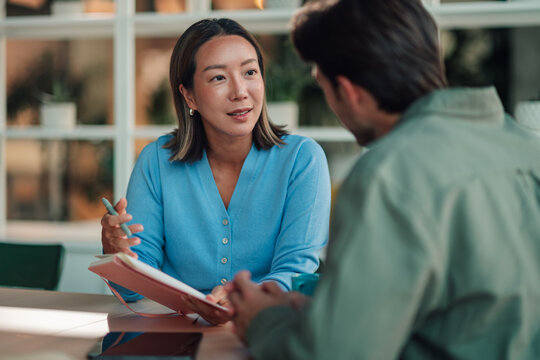 Businesswoman talking with male client during a meeting, discussing project ideas and strategy in modern office setting