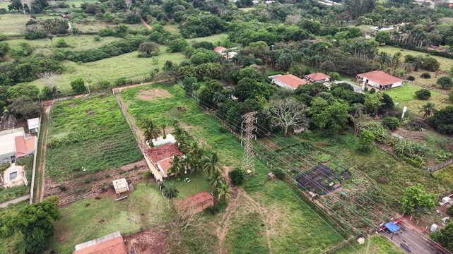 Aerial drone footage captures a rural landscape with houses, fields, and power lines in a time lapse sequence
