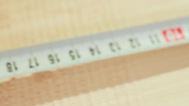 Close up view of hands using metal ruler to measure wooden boards with precision. focus remains on interaction between fingers measuring tape and wood surface
