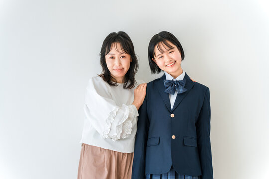 制服姿の高校生の娘に笑顔で寄り添う母親。入学や進学を迎える中学生。