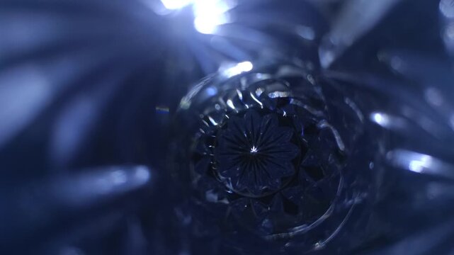 Abstract blue and white lens flare through faceted glass, with sparkling highlights and a circular starburst pattern creating a luminous cinematic motion background