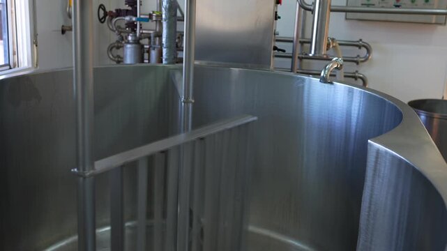Large stainless steel vat with a mixer turning during the cheese making process in a factory