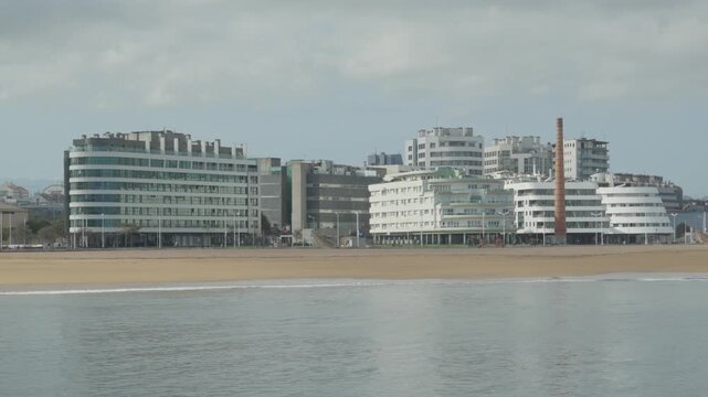 Modern city buildings along the coast of San Lorenzo beach in Gijon, Spain