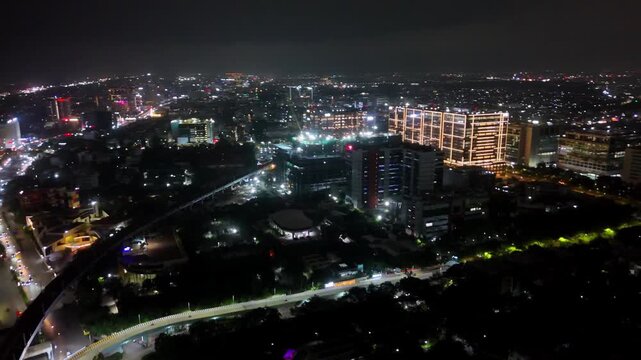Aerial drone footage of DLF, Old Mahabalipuram Road (OMR), Chennai, at night, featuring brightly illuminated office buildings, heavy road traffic, colorful vehicle lights, and surrounding commercial