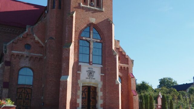 Side view of a historic red brick church with a tall tower in Cacica, Romania.