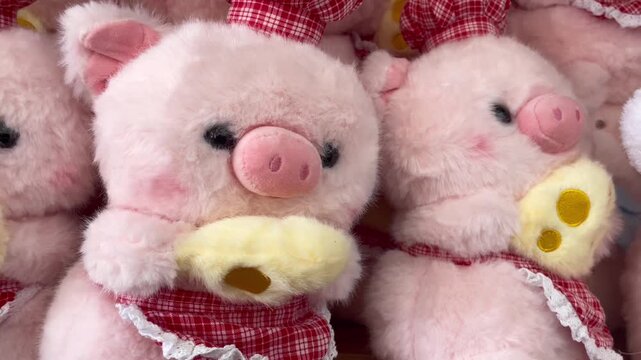 Cute pink pig plush toys and chef stuffed animals. Adorable fluffy piggy dolls wearing red checkered chef hats and matching aprons while holding yellow cheese slices, alongside retail gift shop 