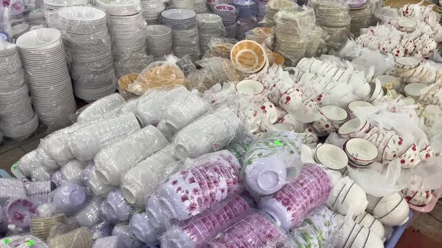 A massive display of ceramic bowls, plates, and dinnerware on retail market shelves. A large collection of kitchenware items featuring stacked white porcelain dishes, floral patterned bowls wrapped 