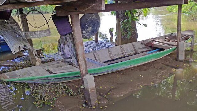 Flooded riverside shelter with boat stranded in mud after water receded
