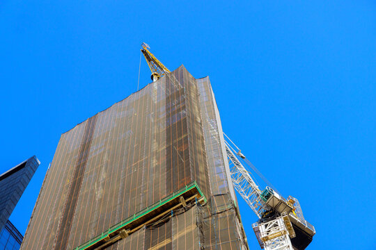 Construction site with crane working on tall building in an urban Manhattan area