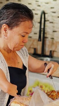Woman with disability slicing freshly baked bread in kitchen