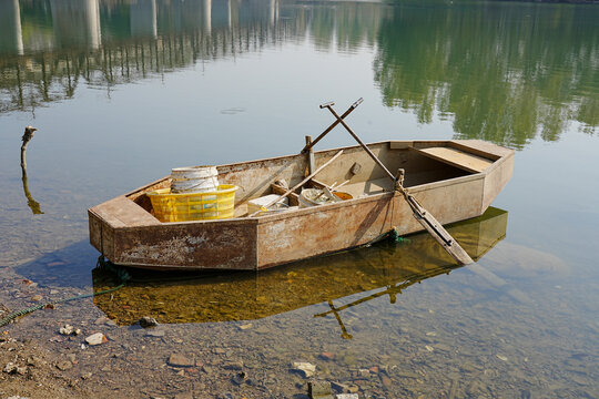 Old rusty metal fishing boat moored in shallow water