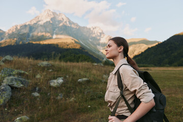 Fototapeta premium A woman hiking with a backpack in an open valley, mountains in the background, capturing a moment of outdoor exploration and scenic nature.