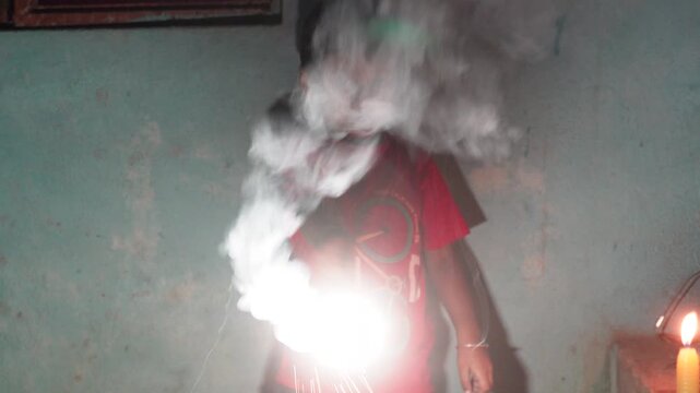 Young child holding a glowing sparkler during diwali celebrations