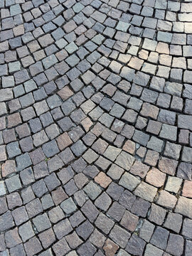 Gray porphyry cobblestone pavement laid in a fan pattern, background texture
