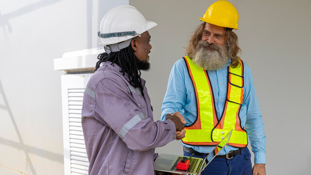 Two construction workers from different generations using a laptop to review progress together, highlighting teamwork, shared experience, and learning in a contruction place