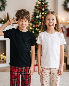 Young boy in blank black tee and girl model in white shirt stand in holiday decorated room. Two kids. Christmas design shirt mockup. Double tee template. Children group, siblings, brother, sister