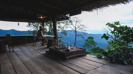 Fototapeta premium A woman sitting on wooden terrace and looking at nature views