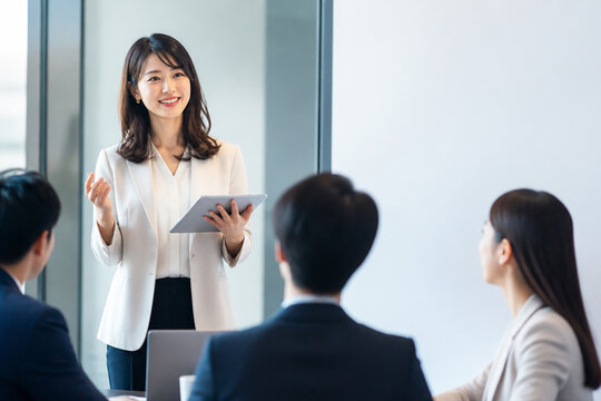 タブレットを持って説明する女性会社員