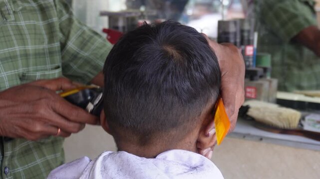 Barber giving a young boy a haircut with electric clippers