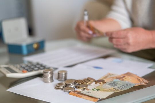 Person counting euro banknotes and coins on a desk with a calculator, managing finances and planning household expenses for savings and financial security