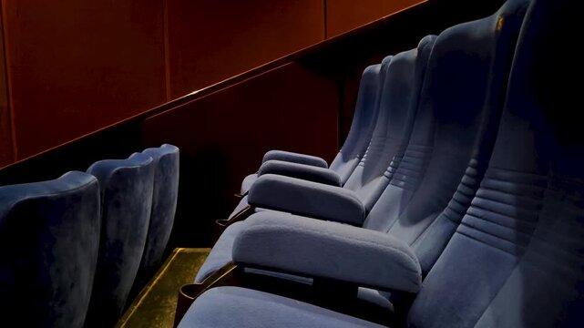 Rows of empty blue seats in a dim movie theater hall, ready for cinema audience