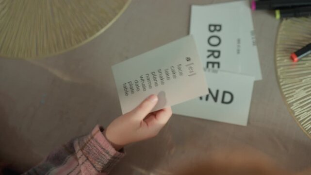Close up view of hands holding and pointing to cards with phonetic transcriptions on table suggesting educational or language learning context phonetics