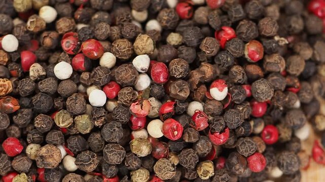Different types of peppercorns on a wooden surface