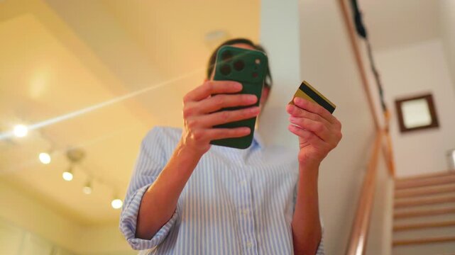 Woman's hands entering credit card details on a smartphone for an online purchase, demonstrating secure e-commerce payment processing and digital banking convenience